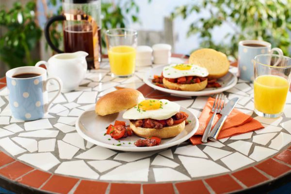 A table with plates and breakfast burgers in an outdoor setting